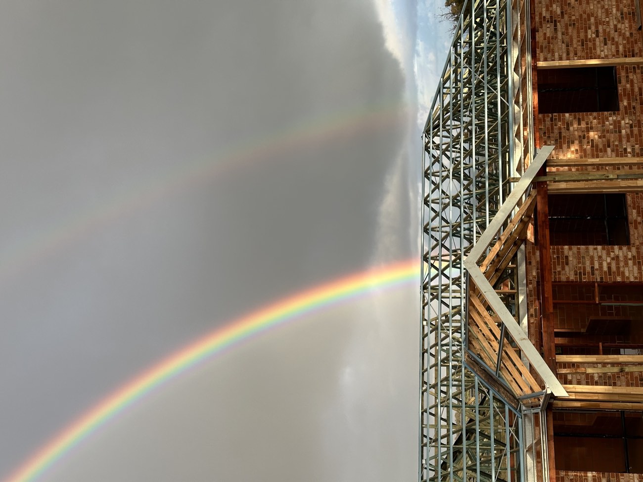 Roof truss frame on a new brick home under a double rainbow